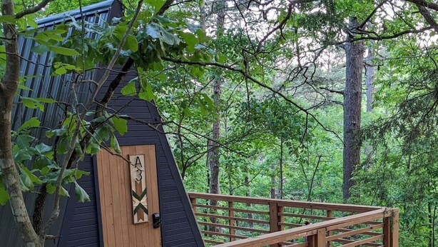 Una terraza de madera que conduce a una cabaña con techo negro y una puerta con la inscripción 'A3'.