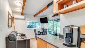 A modern kitchen with a marble countertop, built-in oven, and a coffee machine. There is a dining area with a table and chairs, and a sofa with a coffee table. - Riverfront Sandy Retreat, Fish & Kayak On-Site (Sandy)