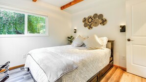 A bedroom with a bed, a window, a wall decoration, and a door. - Riverfront Sandy Retreat, Fish & Kayak On-Site (Sandy)