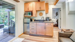 A modern kitchen with wooden cabinets, a central island, and a view to an outdoor deck. - Riverfront Sandy Retreat, Fish & Kayak On-Site (Sandy)