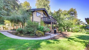 A two-story house with a balcony, surrounded by lush greenery and trees. - Riverfront Sandy Retreat, Fish & Kayak On-Site (Sandy)