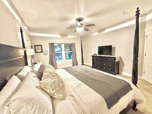 A bedroom with a large bed, a ceiling fan, a dresser, and a television. - Relax & unwind in sun rm yoga rm & private HOT TUB (Eagle)
