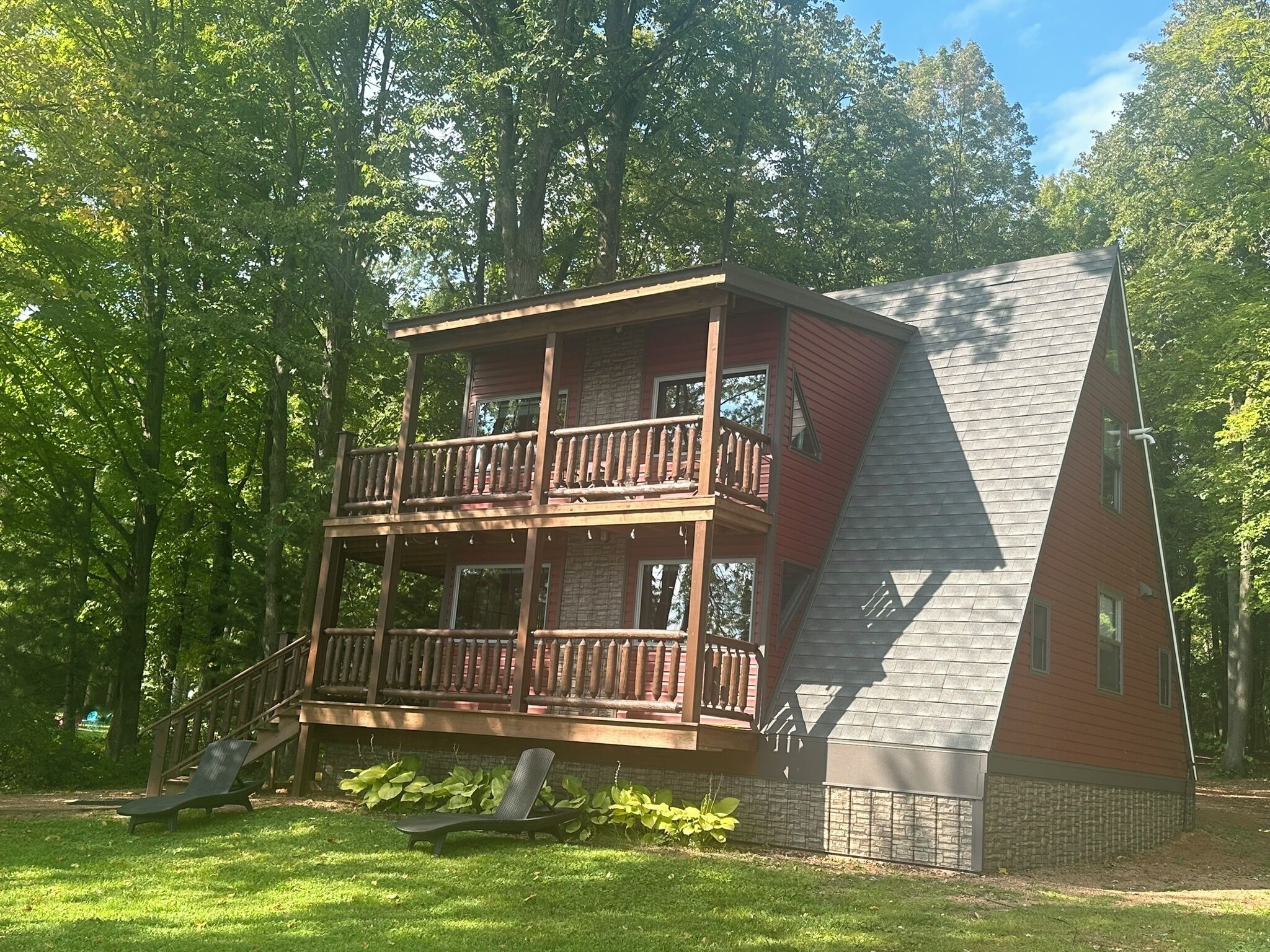A two-story cabin with a balcony, surrounded by trees.