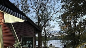 Une terrasse en bois avec une table et des chaises, donnant sur un lac.