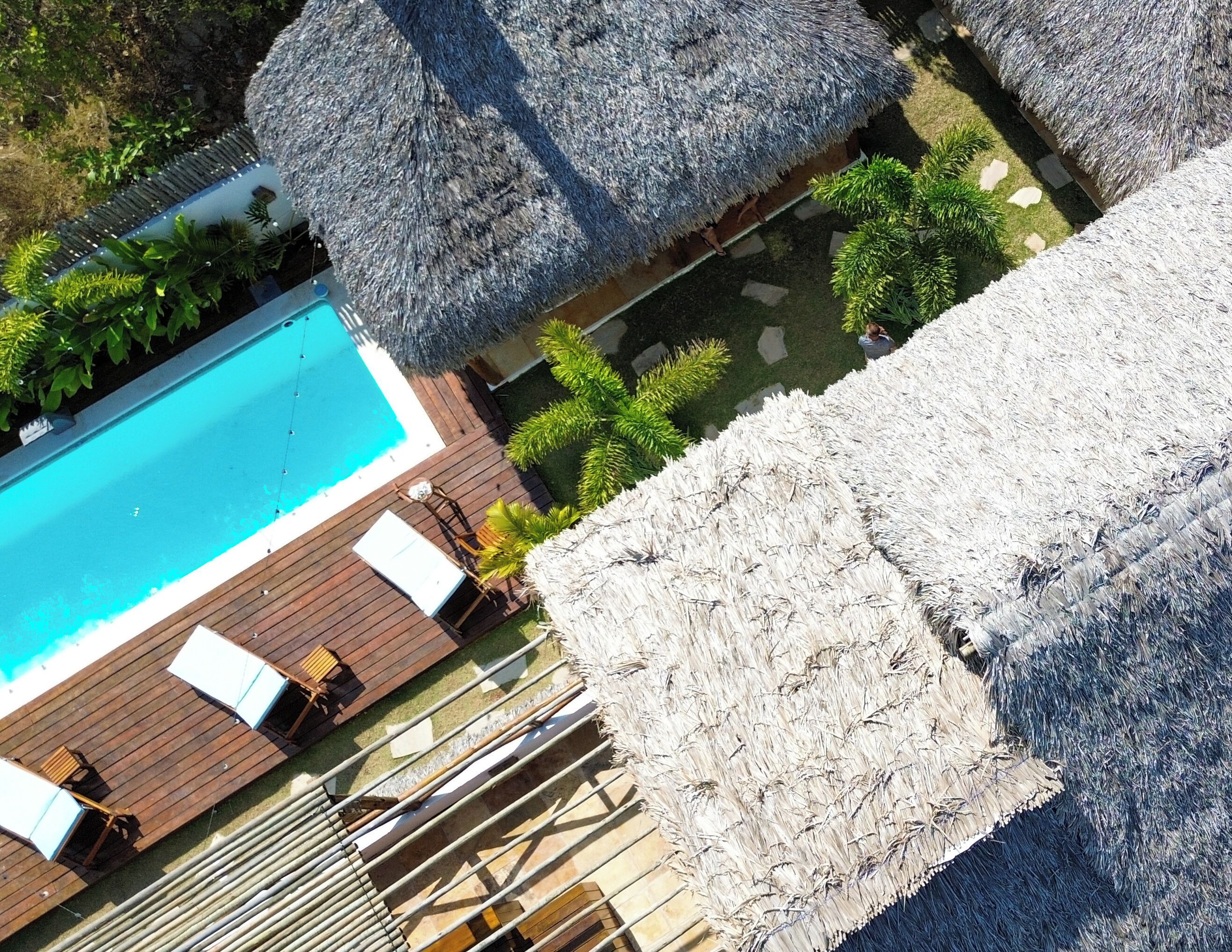 A pool area with thatched umbrellas, wooden deck, and lounge chairs.