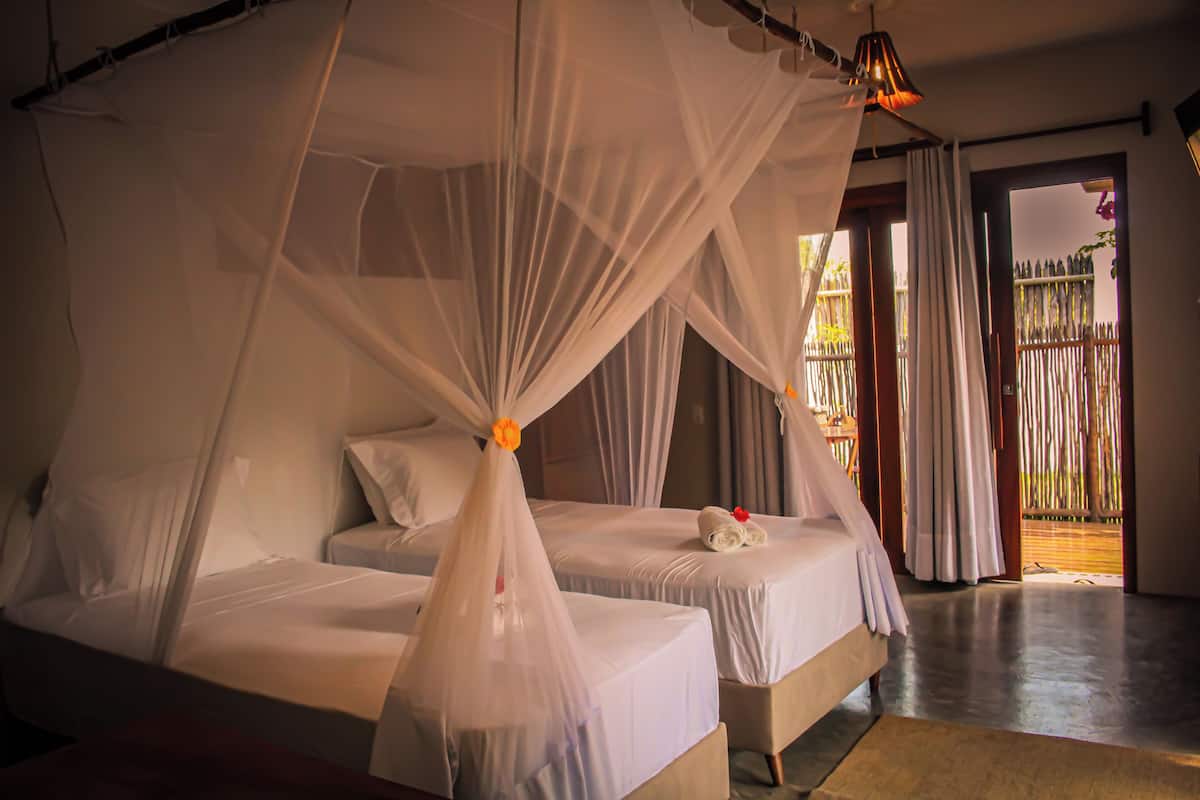 Ein Schlafzimmer mit zwei Betten, jeweils mit weißer Bettwäsche und einem Baldachin.