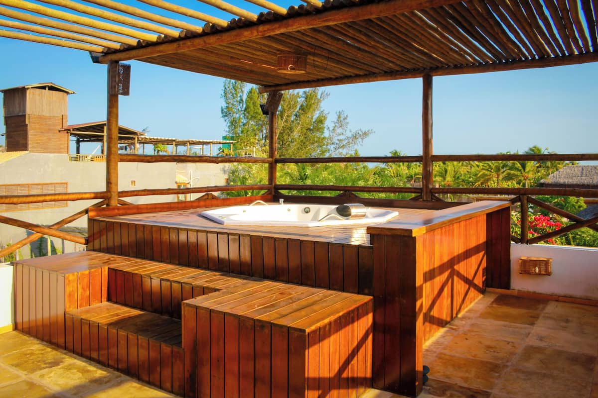 Ein hölzernes Whirlpool mit Stufen und einer Pergola darüber.