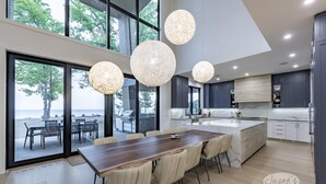 A modern kitchen with a large island, dark cabinets, and pendant lights.
