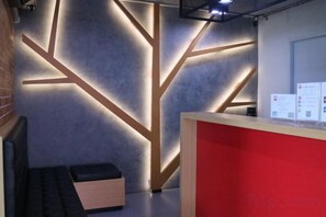 Un área de recepción con diseño moderno, que incluye un mostrador rojo y una pared con patrones geométricos.