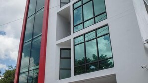 Un edifici modern amb diversos pisos, grans finestres i un detall vermell a la façana.