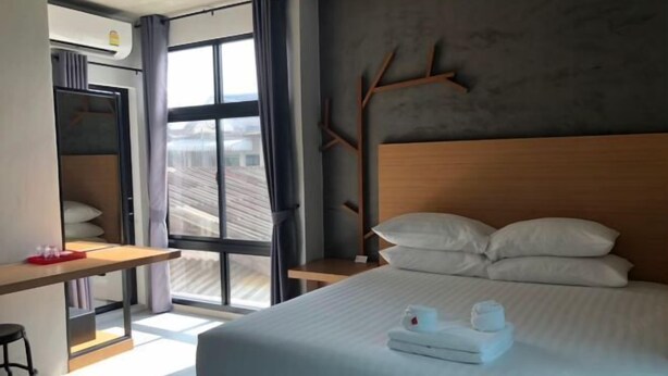 Habitació d'hotel moderna amb un llit gran, un escriptori i una finestra amb cortines.