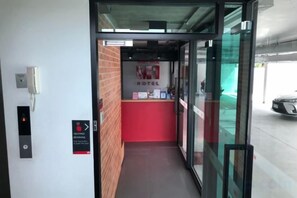 Un espace d’accueil d’hôtel avec un comptoir rouge, un téléphone et un panneau indiquant le menu du service en chambre.