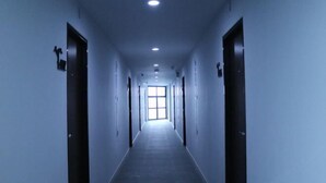 Un passadís llarg i estret, amb portes a banda i banda, que condueix a una finestra ampla i lluminosa al final.