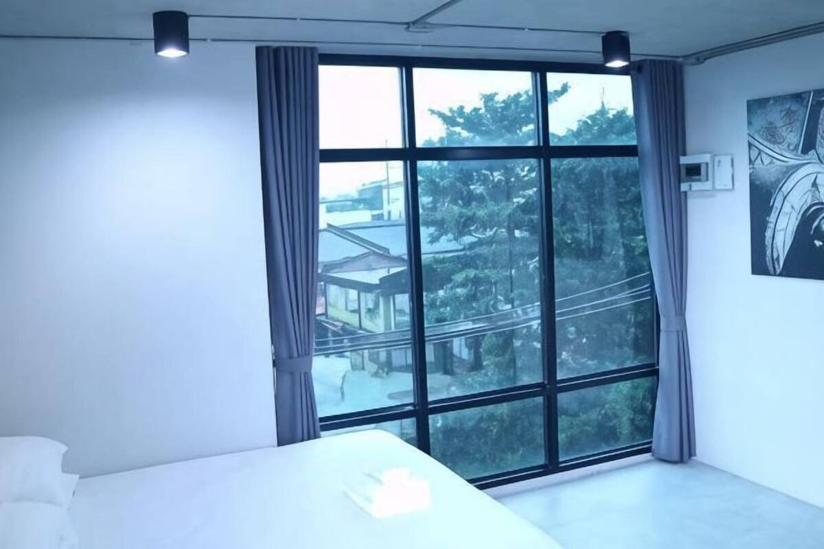 Un dormitorio con un ventanal grande, una cama y un aire acondicionado instalado en la pared.