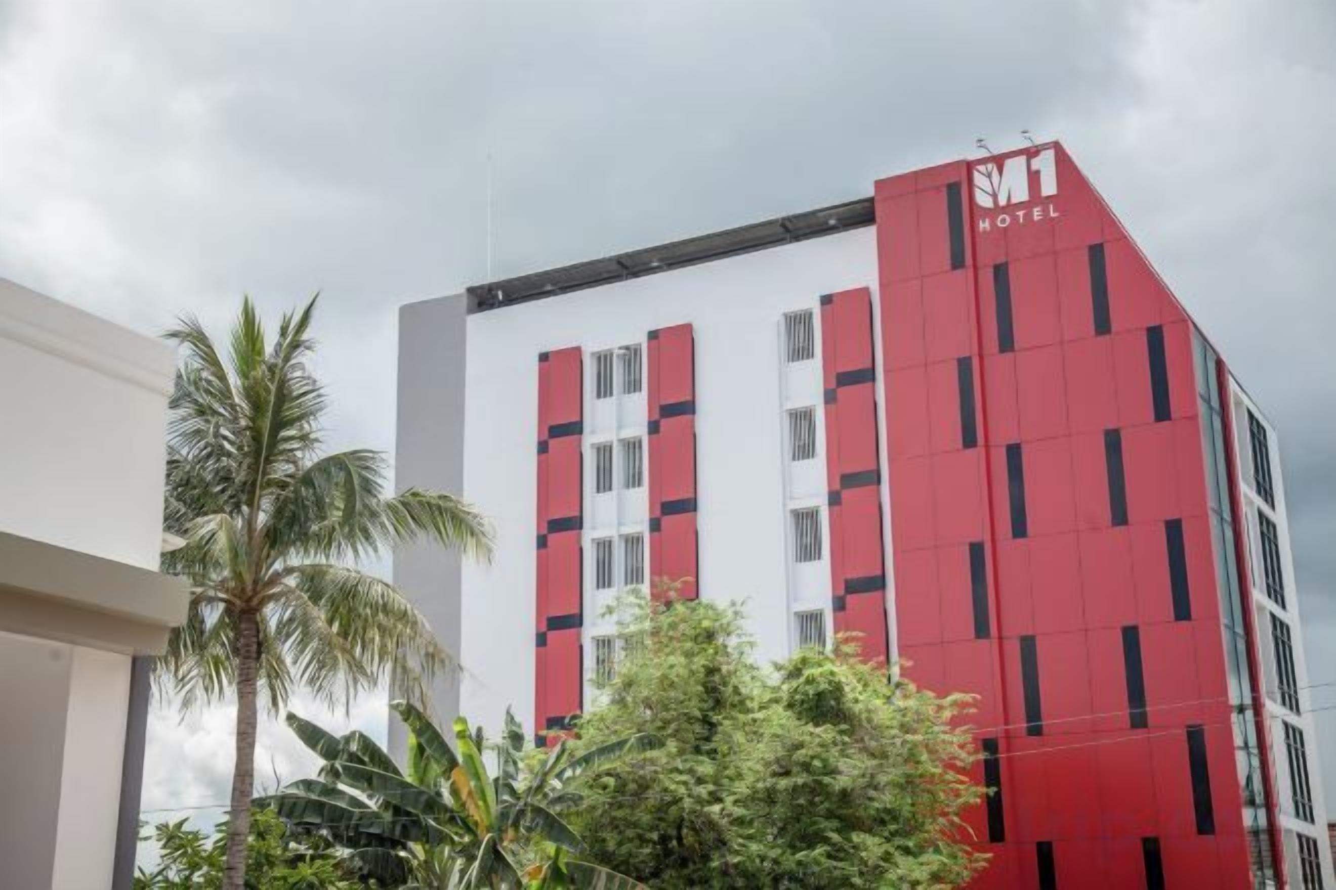 A hotel with a red and white facade, multiple floors, and a visible logo.