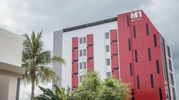 A hotel with a red and white facade, multiple floors, and a visible logo.