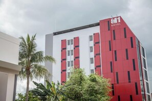 Un hotel con fachada roja y blanca, varios pisos y un logotipo visible.