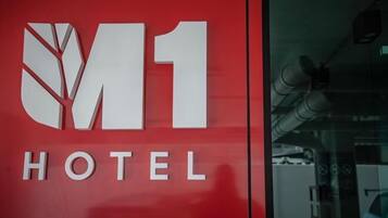 A red wall with the M1 Hotel logo and the word "HOTEL" below it.