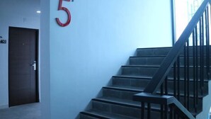 Una escala amb barana metàl·lica que condueix a una plataforma. Al mur es pot veure un gran número vermell, el '5'.