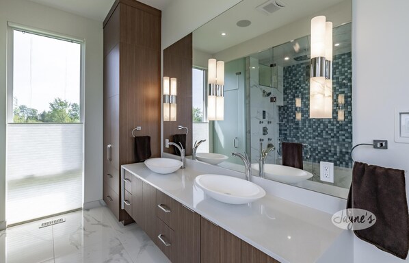 Un baño moderno con dos lavamanos, un espejo grande y una cabina de ducha de vidrio.