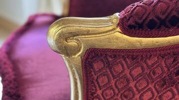 A close-up of a chair with a gold frame and a textured red cushion.