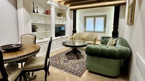 A dining area with a round table and chairs, a green sofa, and a herringbone-patterned floor.