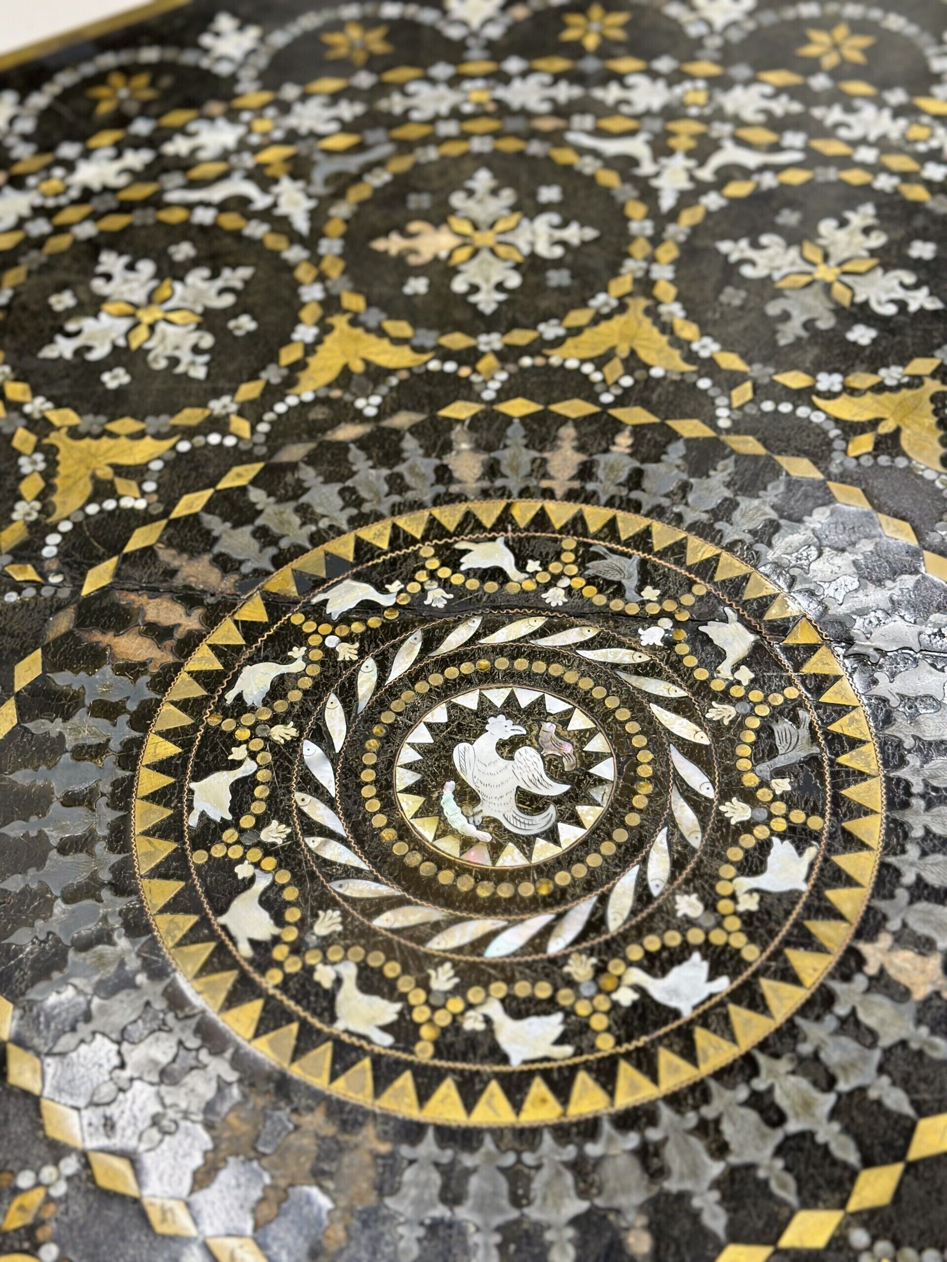 A detailed mosaic floor with geometric patterns and a central rooster design.