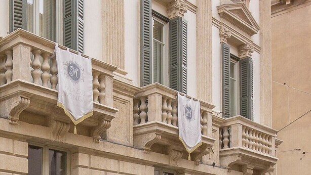 A building facade with classical architecture, featuring ornate balconies and decorative sculptures.