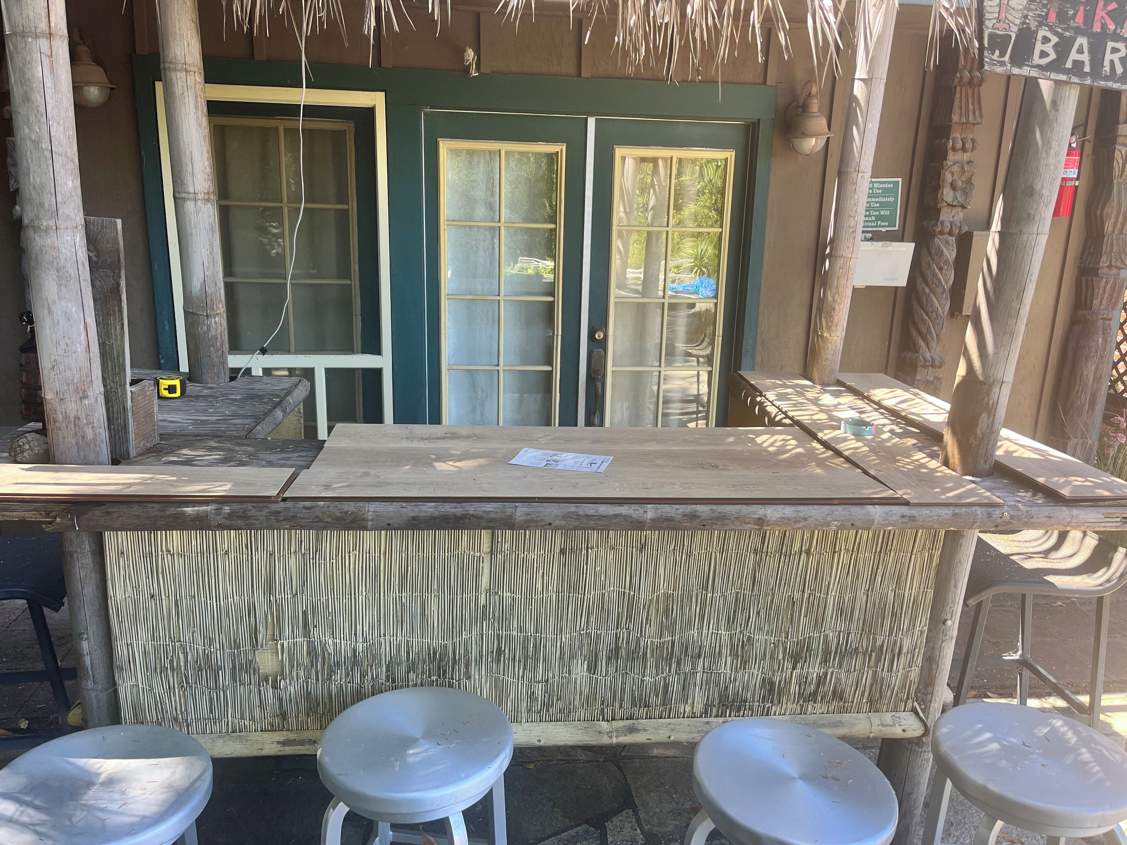 A wooden bar area with a counter and stools, large windows, and a bamboo wall.