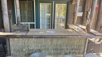 A wooden bar area with a counter and stools, large windows, and a bamboo wall.