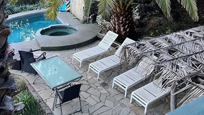 Ein Poolbereich mit Liegestühlen und einem Whirlpool, umgeben von Palmen.