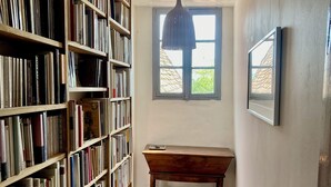 Eine Bibliothek mit Holzbögen, einer Holzbank und einem Fenster mit Blick auf ein Gebäude.