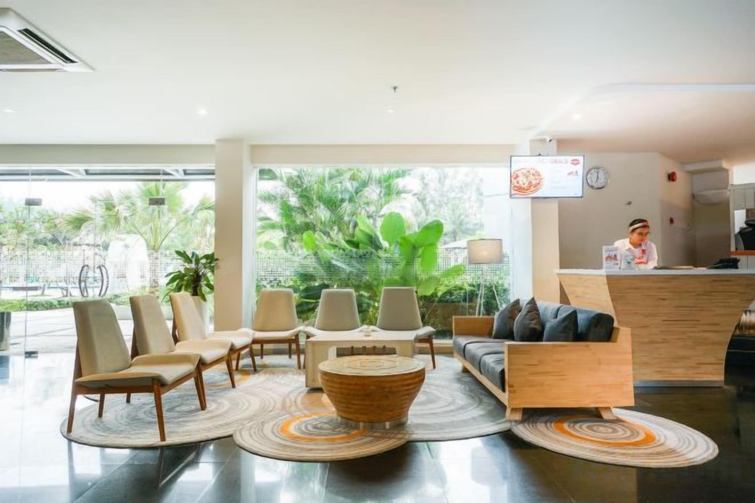 A hotel lobby with a reception desk, seating area, and large windows.