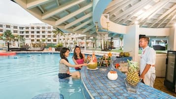 An indoor swimming pool with a bar area, lounge chairs, and a poolside restaurant.