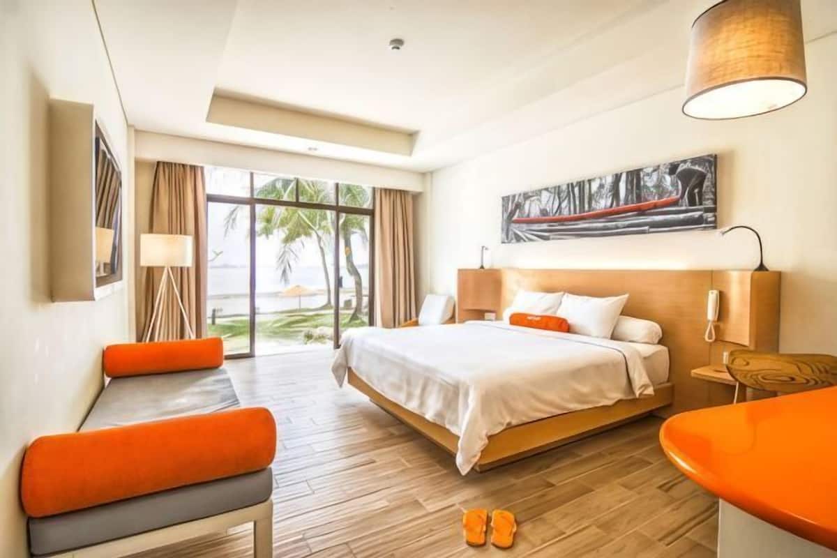 A hotel room with a bed, seating area, and a view of the outdoors.