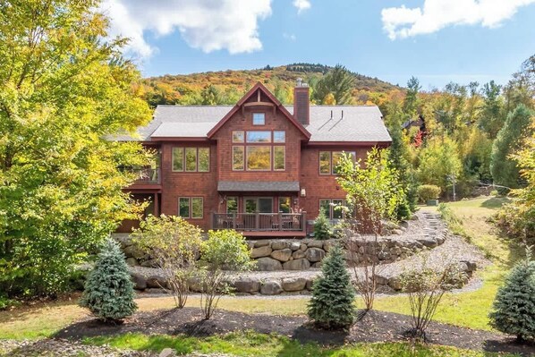 Situated in a wooded area, this house features a gabled roof, front porch, and multiple windows.