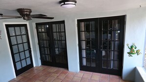 A room with a tiled floor, a ceiling fan, and two black-framed doors with glass panels.