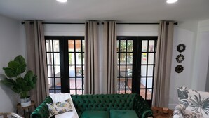 A green sofa with a white throw blanket and a large potted plant.