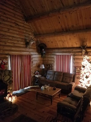 A log cabin interior with a sofa, a coffee table, and a fireplace.