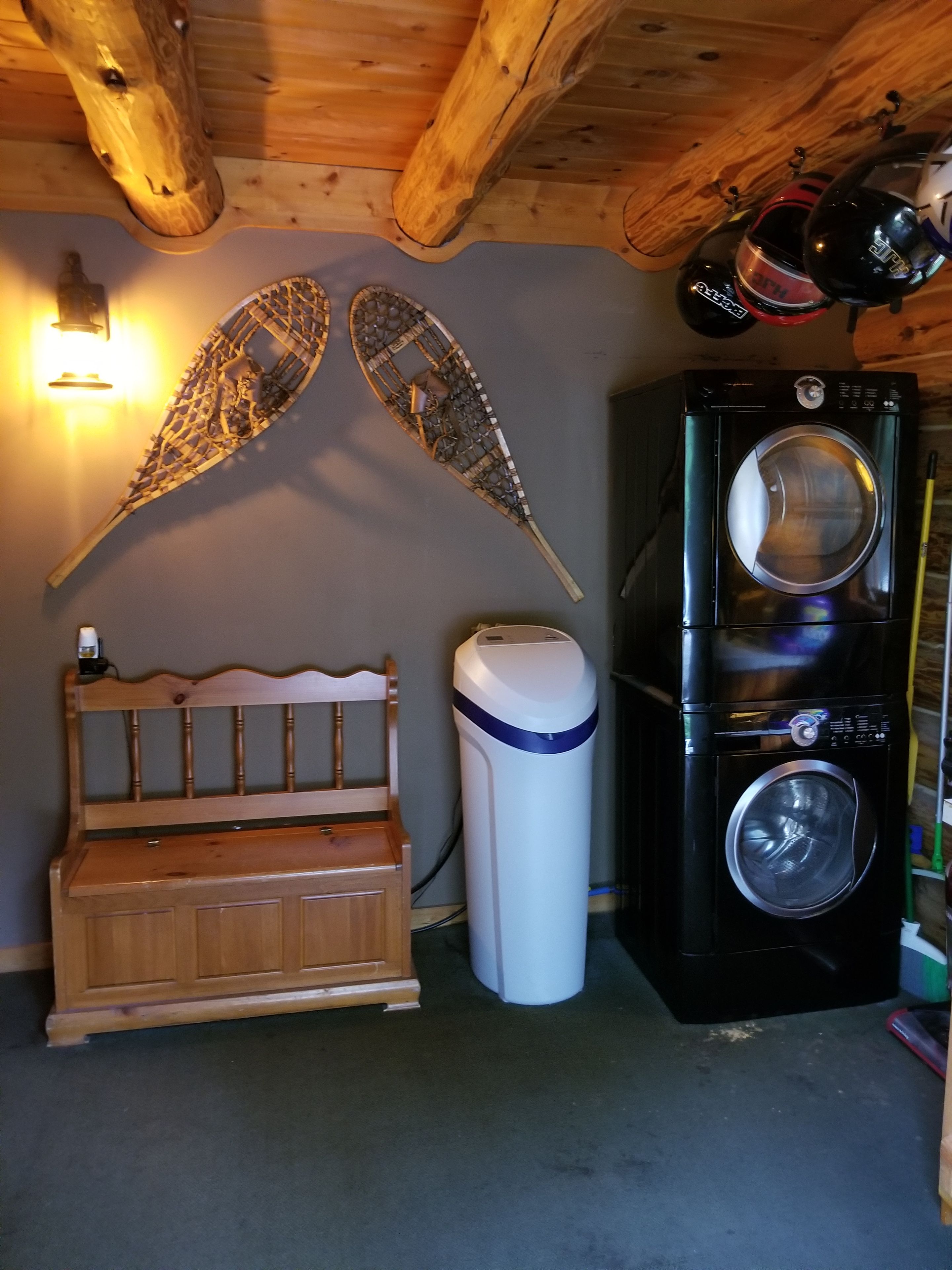 A room with a wooden bench, a wall-mounted decorative piece, and a black washing machine.