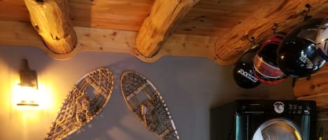 A room with a wooden bench, a wall-mounted decorative piece, and a black washing machine.
