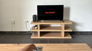 A television on a wooden stand with a remote control in front. - Trésor Caché d'Amazonie Oasis de Calme (Cayenne)