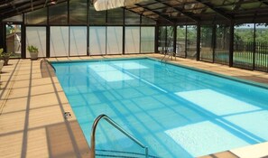 An indoor swimming pool with a clear view of the surrounding area, including a fenced garden and a covered roof structure. - 2 BR at Pointe Royale Golf Course. Steps from Lake Taneycomo. Gorgeous views (Branson)
