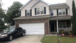 Une maison à deux étages avec un garage, une allée et une pelouse.