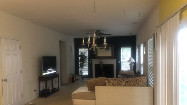 Un salon avec un canapé, un téléviseur et un lustre.