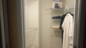 Un dressing accessible sans porte, doté d’étagères ouvertes, d’une tringle à vêtements et d’un petit tabouret.