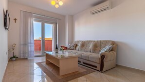Een moderne woonkamer met een bank, een bijzettafeltje en een glazen deur naar een balkon.