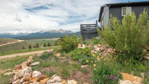 A house with a view of mountains, a garden with rocks and flowers, and a wooden fence. - Sweet Dreams -MtnViews & Hot Tub (Leadville)