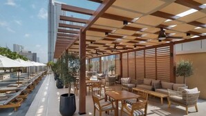An outdoor seating area with wooden furniture and a pergola structure. - Holistay Luxury Homes,  Down Town Direct Access Dubai Mall (Dubai)