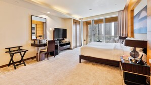 A modern hotel room with a large bed, a desk with a TV, and a view of the city through large windows. - Holistay Luxury Homes,  Down Town Direct Access Dubai Mall (Dubai)